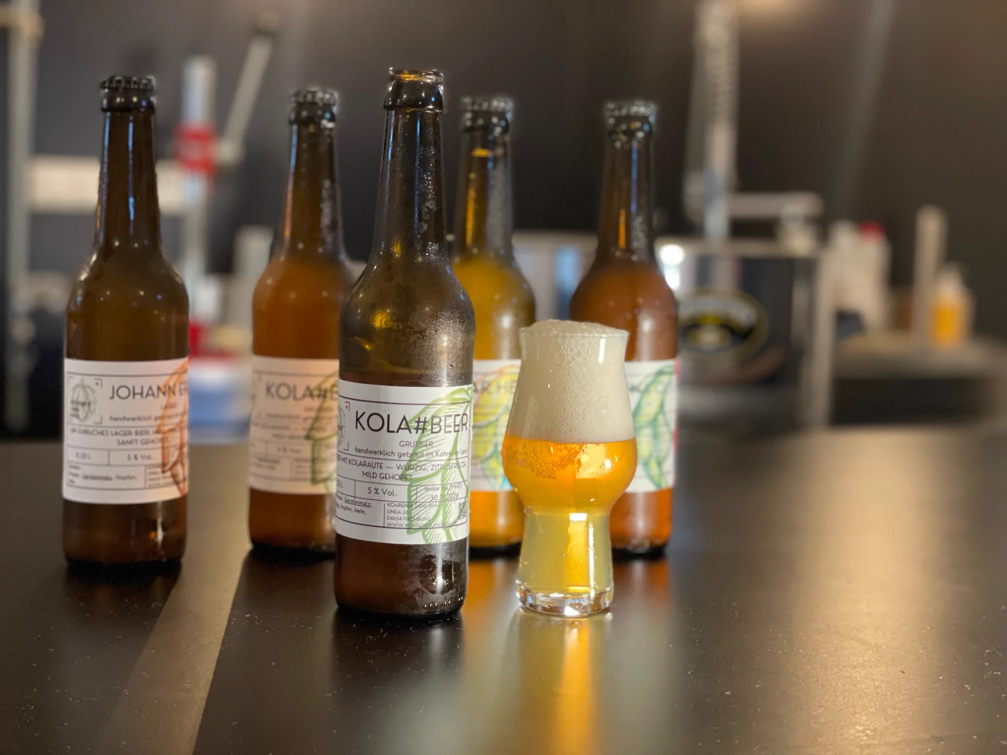 Flaschen von Kohrener Land Bräu mit einem gefüllten Bierglas im Brauatelier